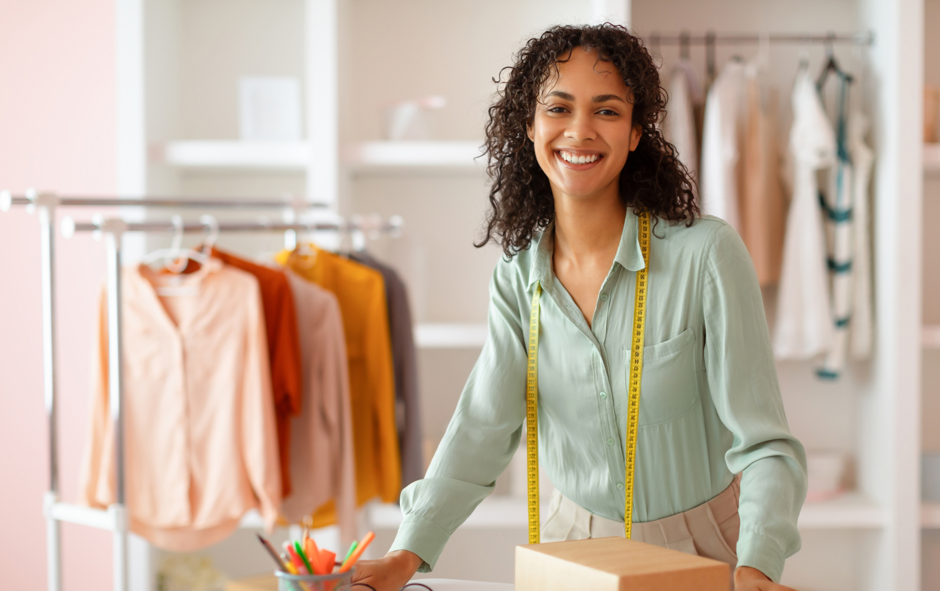 Mujer de pie junto a una mesa, con una caja sobre ella, mostrando una expresión de alegría y curiosidad.